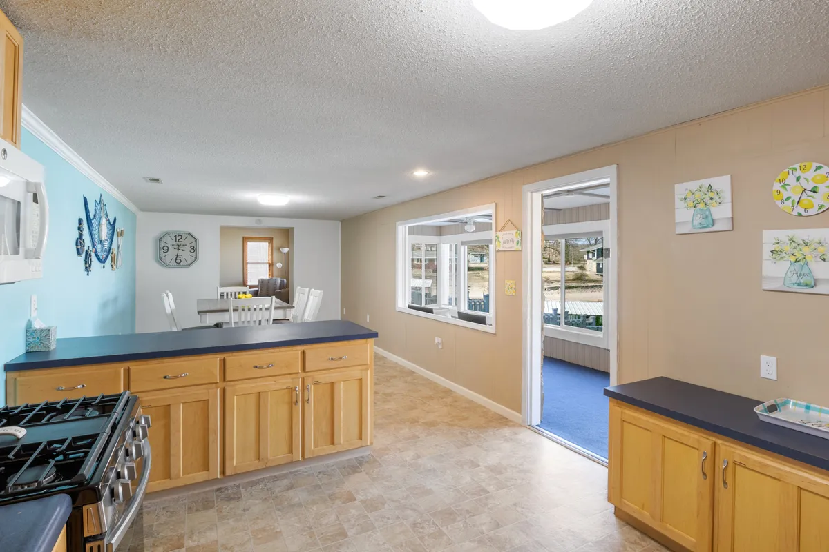 A kitchen counter seamlessly transitions into a cozy dining area, both spaces bathed in natural light from windows. The scene exudes a welcoming, homey atmosphere, perfect for family gatherings and casual dining.