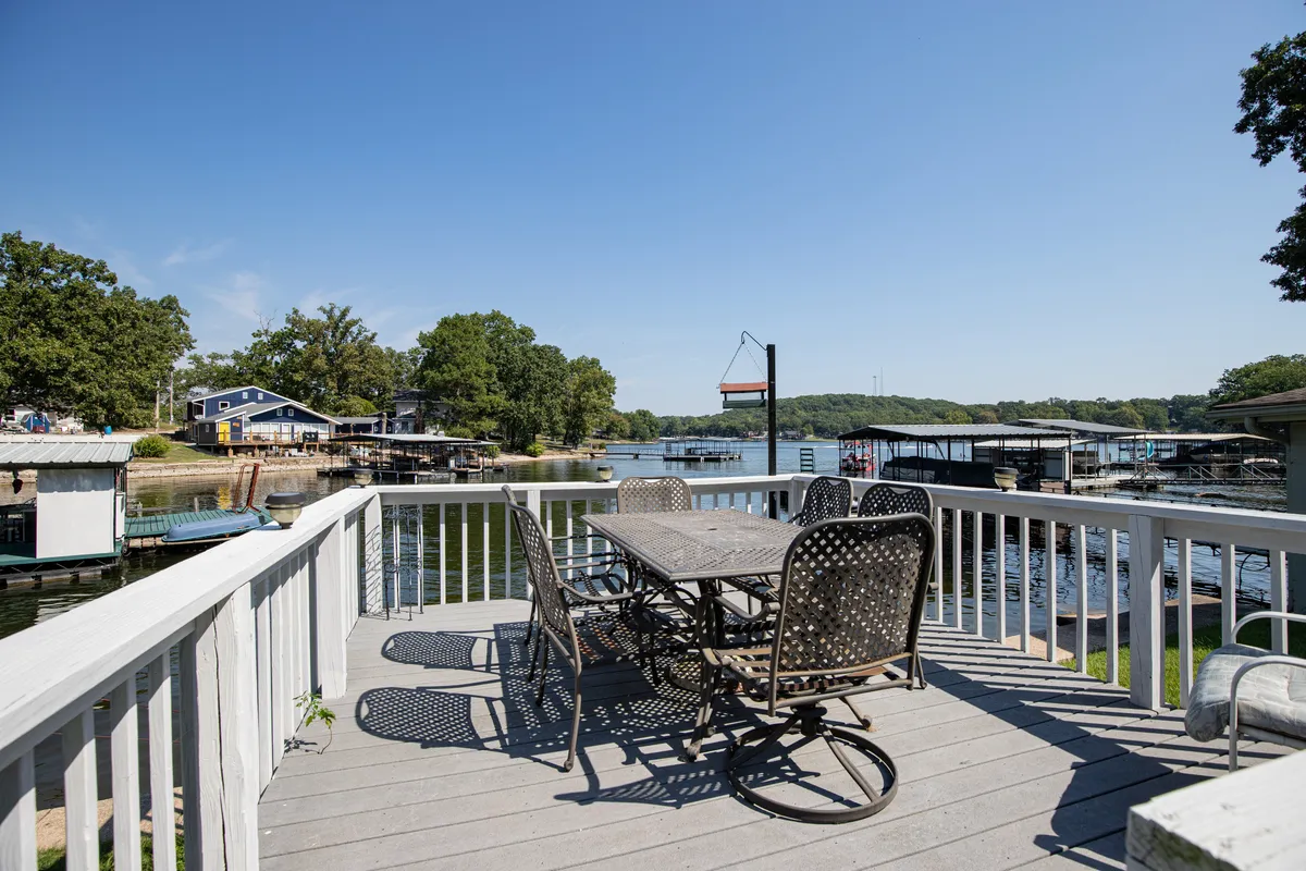 An exterior dining table is set with a stunning water view and surrounded by greenery and boats. The scene suggests outdoor dining, relaxed conversation, and easy access to lake activities—mirroring the lifestyle enjoyed by guests exploring local eateries and nature spots.