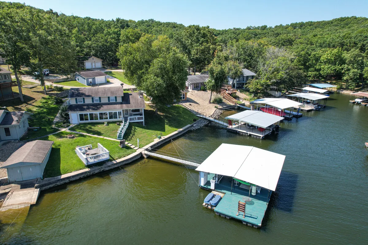 This exterior image showcases a serene lake bordered by boathouses, lush greenery, and residential buildings. The view offers a sense of the vibrant lake culture, with opportunities for boating, fishing, and relaxing by the water. The tranquil atmosphere is highlighted by the soft light, suggesting either sunrise or sunset.