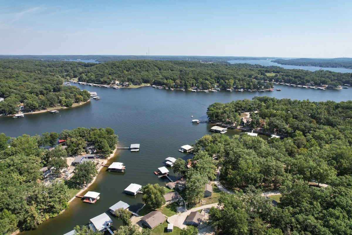 A panoramic lake scene featuring docks, vibrant greenery, and nearby homes. The image conveys a sense of community, inviting visitors to explore different docks and fishing spots along the Gravois Arm.