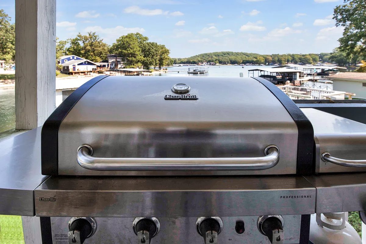 A lakeside grill area with a clear view of the water, surrounded by greenery. The grill is set up for outdoor cooking and gatherings, while the lake in the background hints at easy transitions between water play and relaxed meals by the shore.